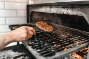 Cook hands prepares smoky meat on grill oven